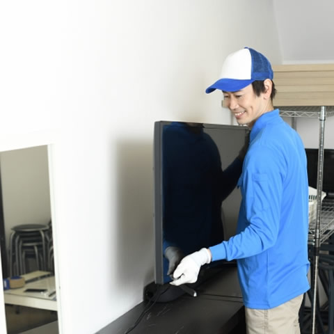 テレビを持ち上げる作業員
